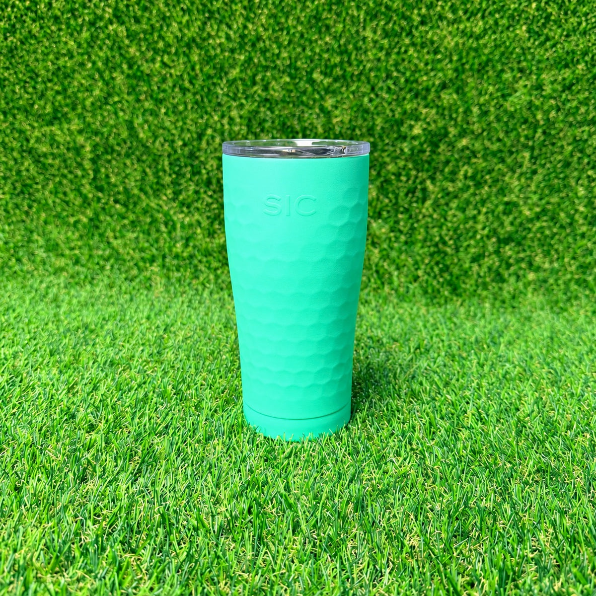 SIC Hammered Mint 20 oz. tumbler with textured finish and clear lid on green turf