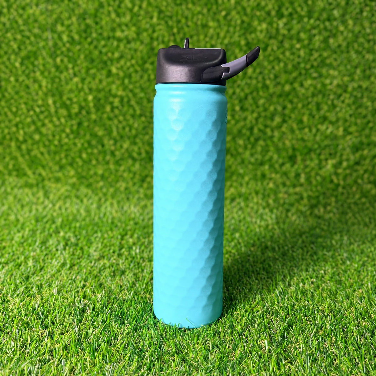 SIC Hammered Seafoam 27 oz. sport bottle with black lid on green turf