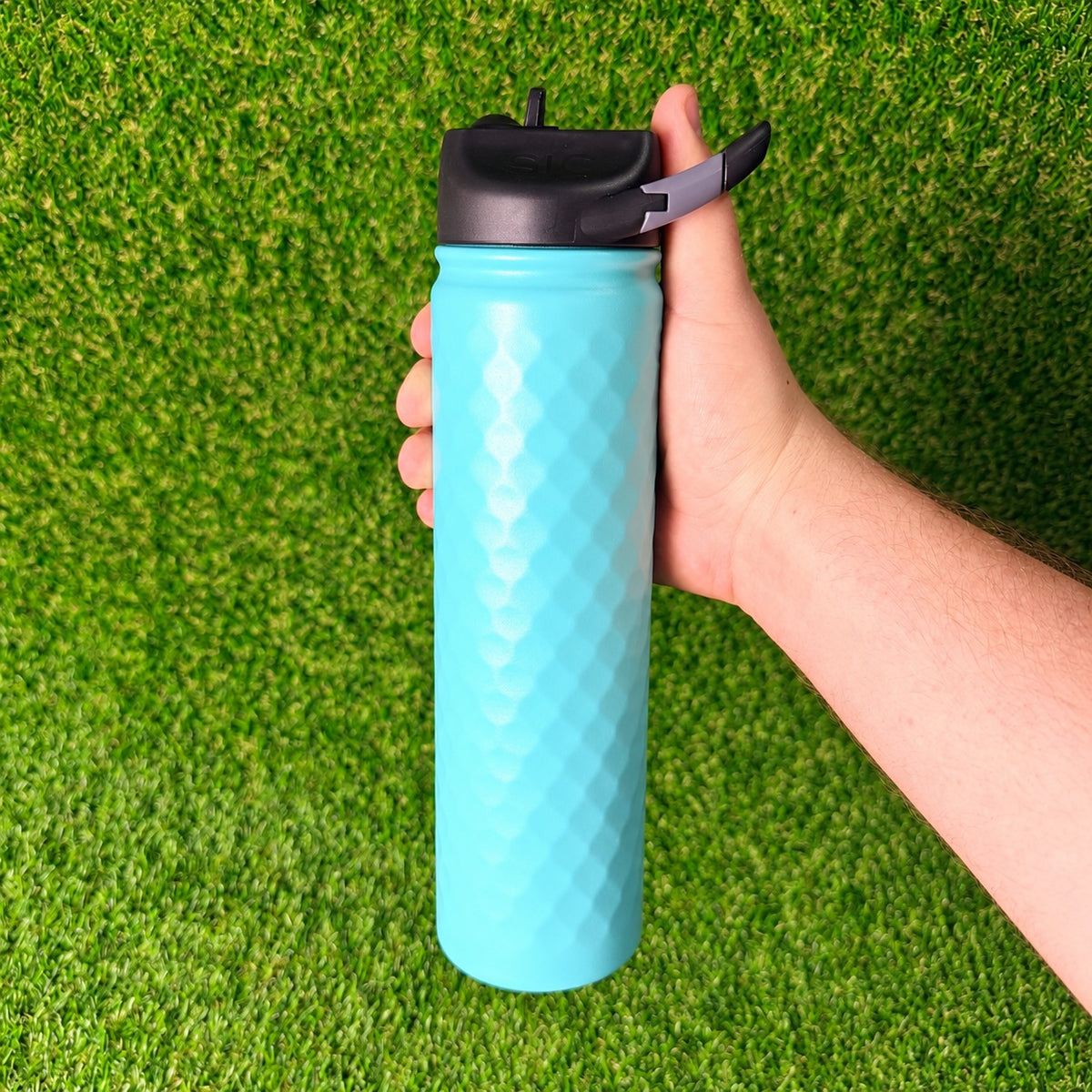 Hand holding a SIC Hammered Seafoam 27 oz. sport bottle with black lid