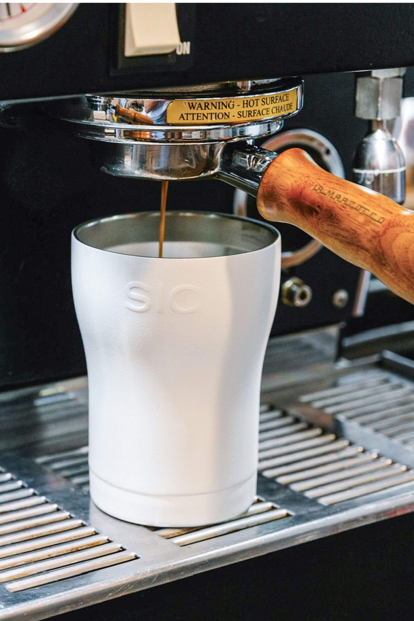 Coffee being poured into a stainless steel cup