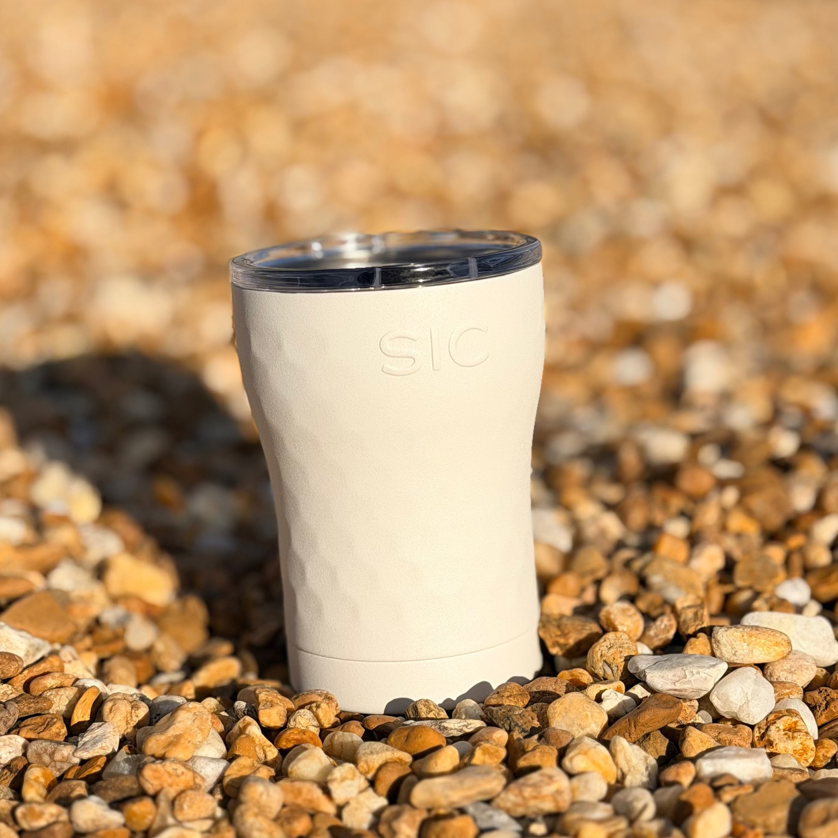 White tumbler with blue rim on pebbles