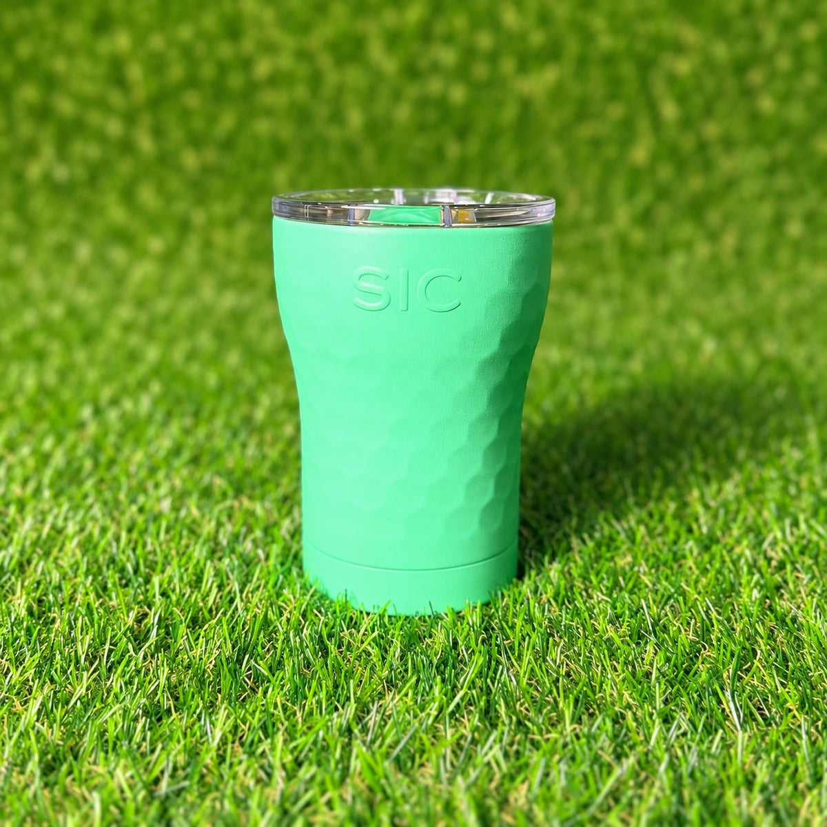 SIC Hammered Mint 12 oz. tumbler with textured finish and clear lid on green turf