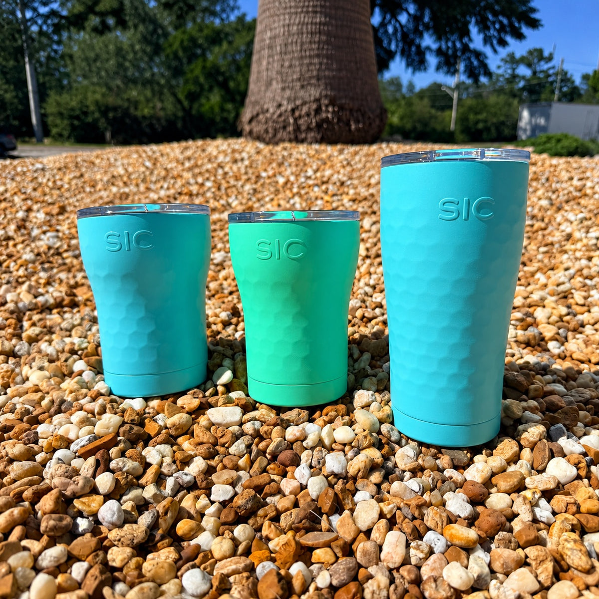 SIC Hammered Mint 12 oz. tumbler with Hammered Seafoam 12 oz. and 20 oz. tumblers on pebbles