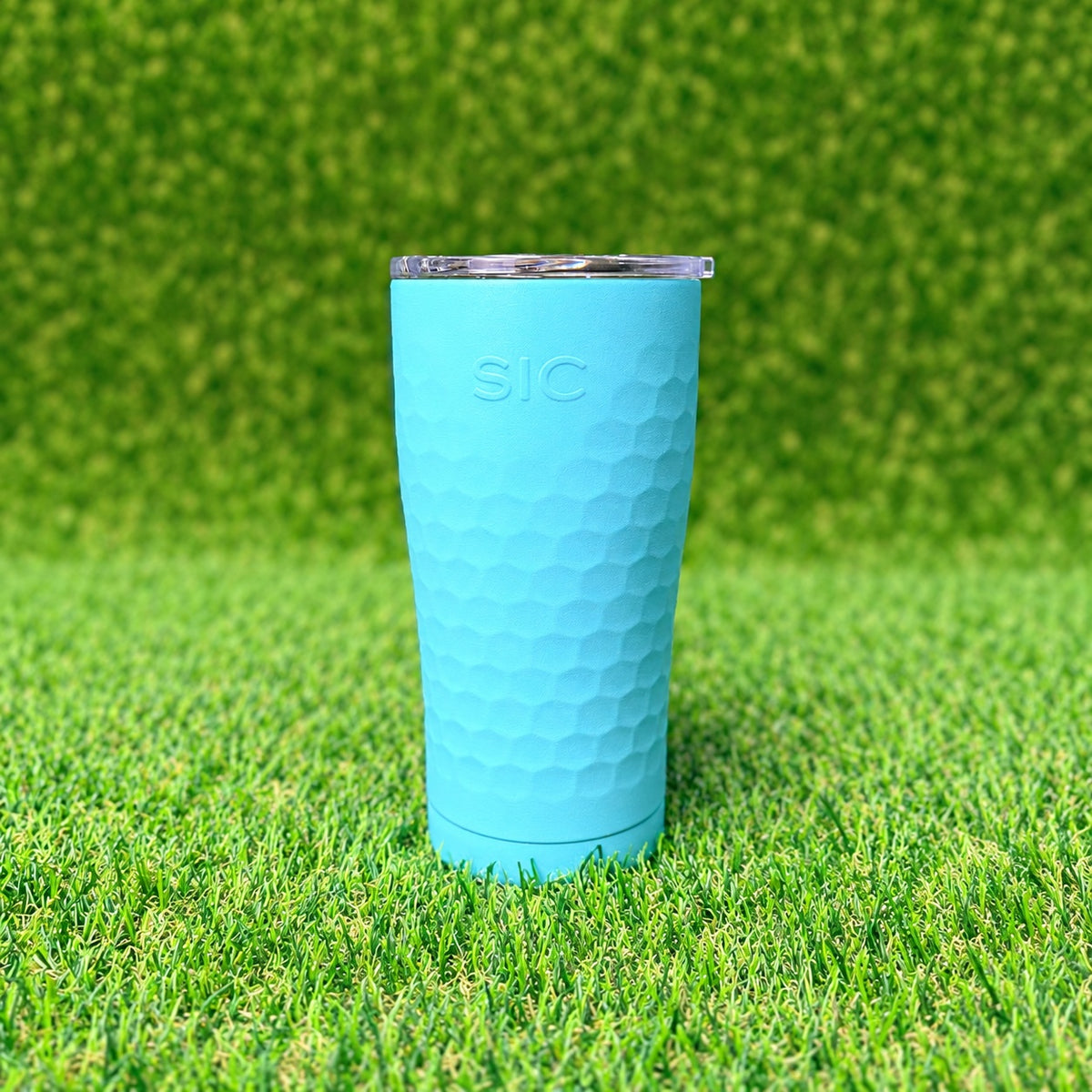 SIC Hammered Seafoam 20 oz. tumbler with clear lid on green turf